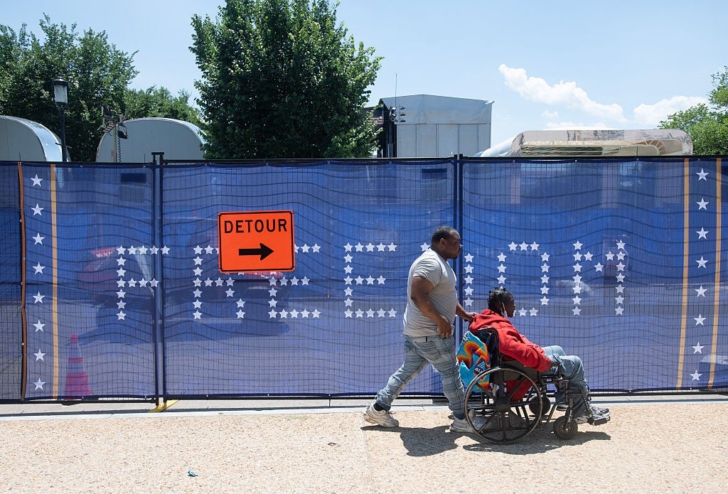 Person pushing different successful a wheelchair past a fenced motion with "FREEDOM" partially obscured by a detour motion with an arrow