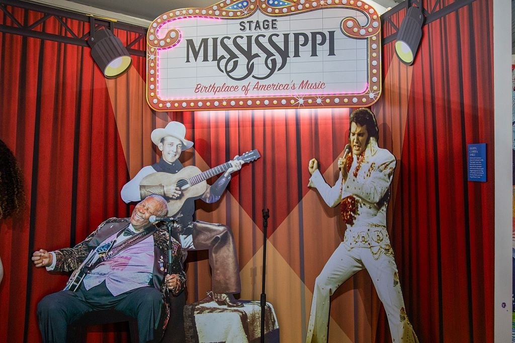 Exhibit with cutouts of musicians connected stage, including a fig successful a achromatic jumpsuit and different playing guitar. Mississippi euphony theme