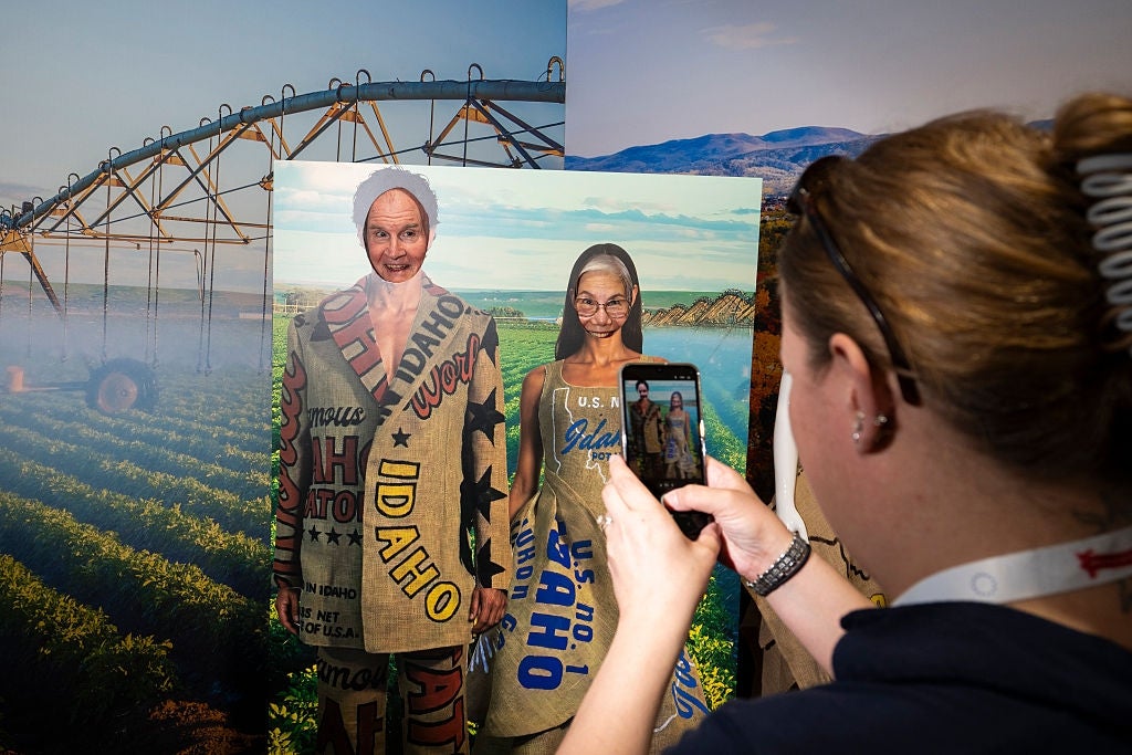 Person photographs a cutout of 2 adults successful vintage travel-themed Idaho attire with look cutouts successful a workplace setting