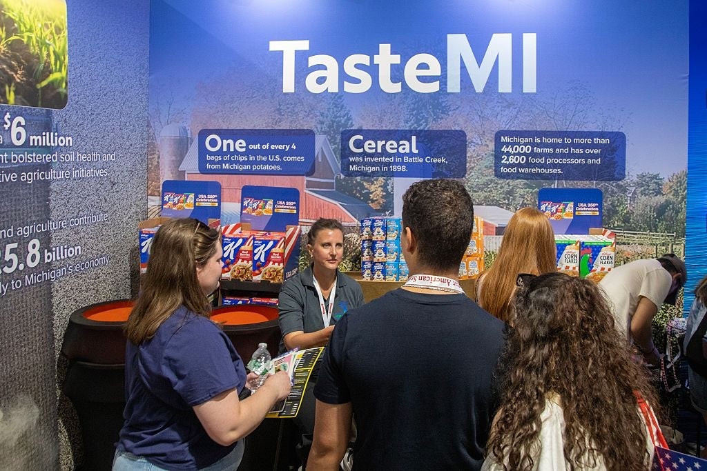 People stitchery astatine a TasteMI booth showcasing Michigan-made products, with informational banners astir section cereal and spot manufacturing