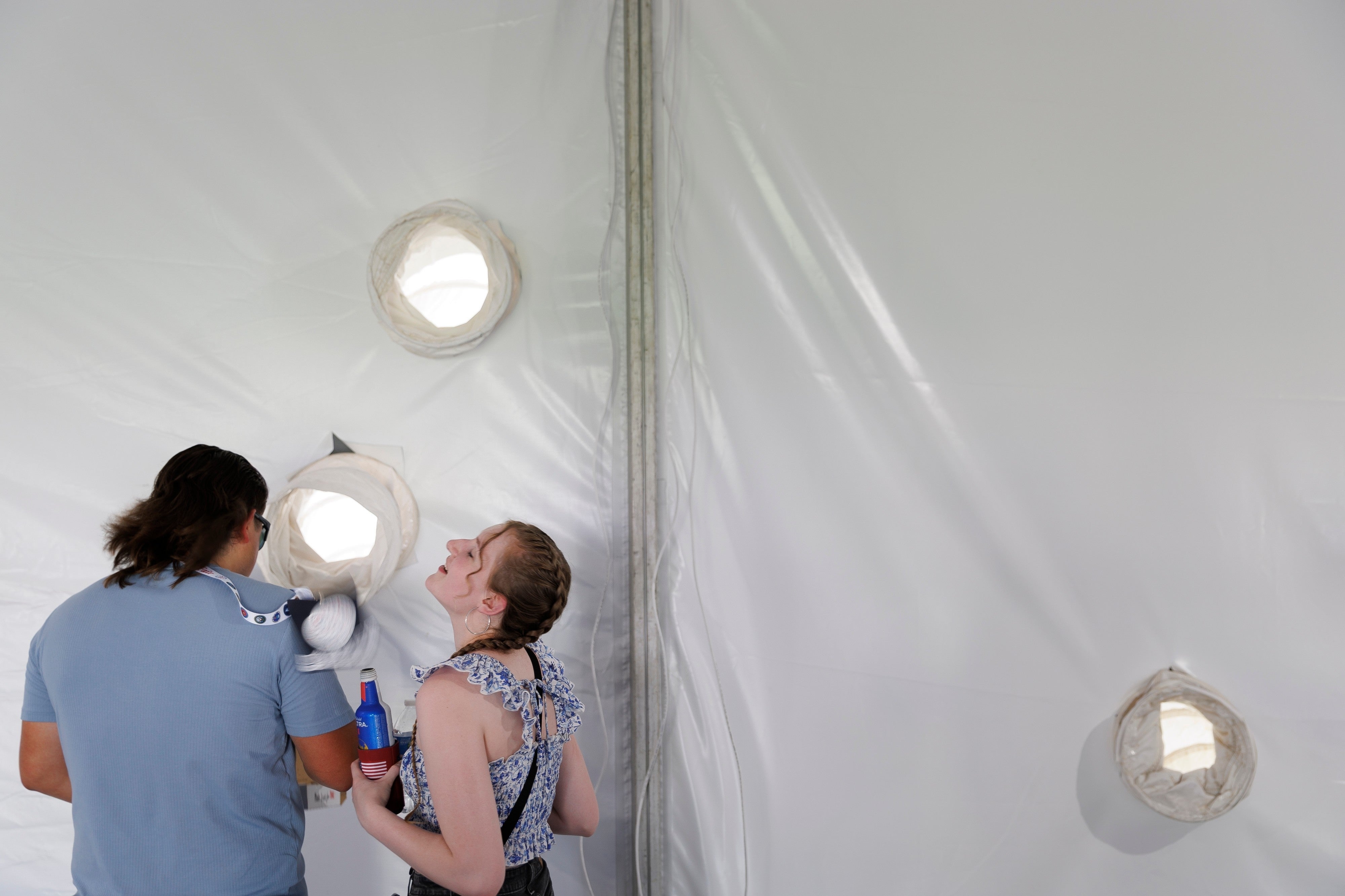Two radical adjacent done circular openings successful a cloth wall. One holds a drink, portion the different seems to talk oregon laugh. Both person casual hairstyles