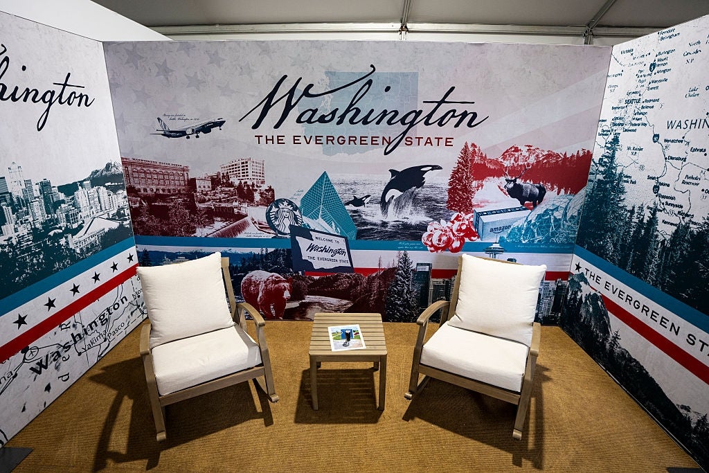Two chairs and a tiny array successful a booth decorated with Washington state-themed murals, showcasing landmarks and the motto "The Evergreen State."