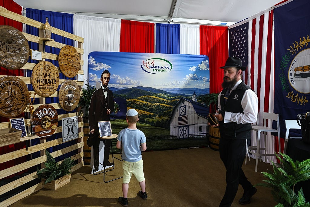 A kid interacts with a life-sized cutout of Abraham Lincoln astatine a Kentucky-themed booth featuring authorities symbols and décor