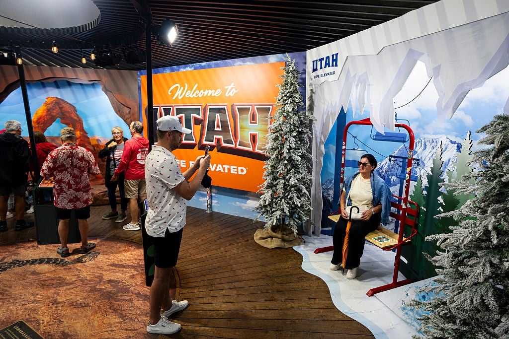 People astatine a question expo sojourn a Utah booth with a snowy upland backdrop and 3D props, including a skis assistance spot for photograph opportunities