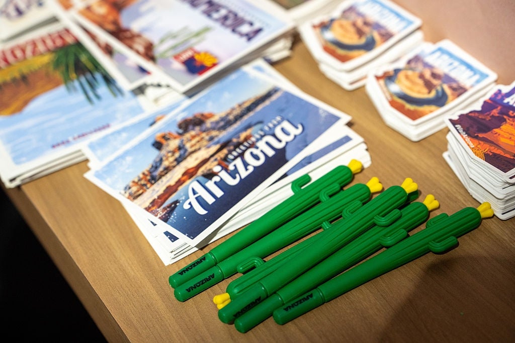 Postcards with "Arizona" substance and cactus-shaped pens arranged connected a table