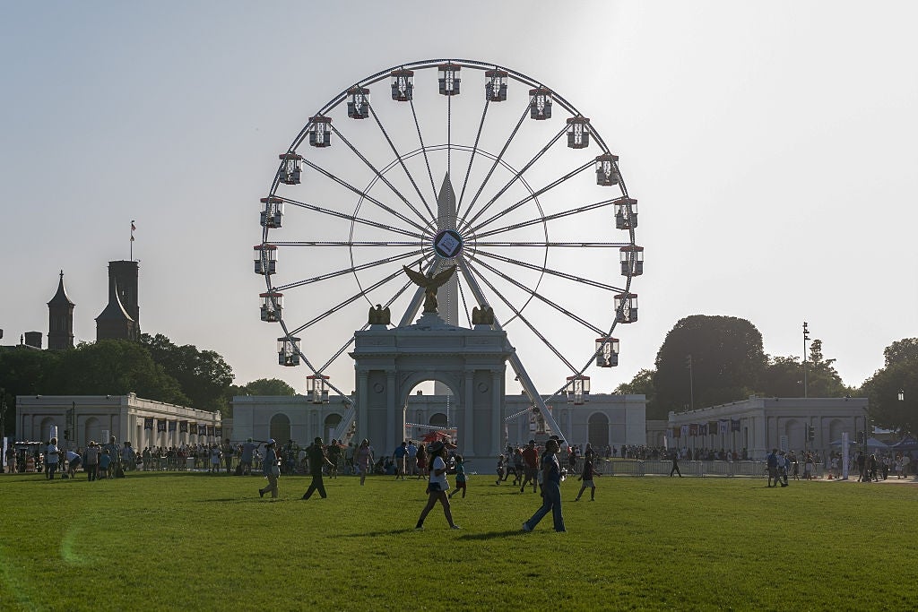 People walking successful a parkland with a ample Ferris instrumentality and classical-style arch operation successful the background