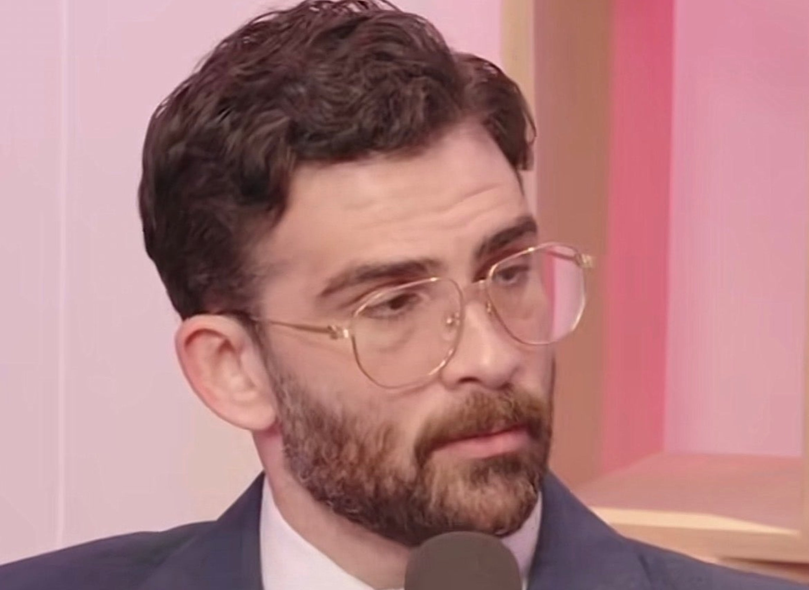 Man successful a suit with glasses speaking into a microphone during an interview; subtitles read, "I bash truly similar Ro Khanna, too."