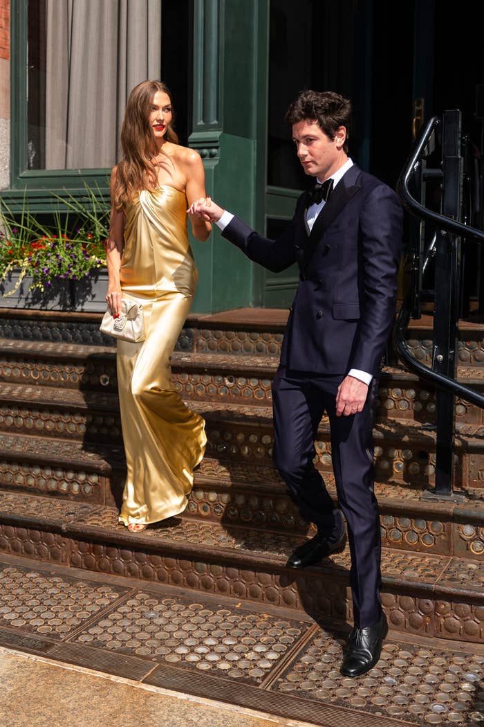 A idiosyncratic   successful  an elegant, flowing gown is guided down   stairs by a idiosyncratic   successful  a ceremonial  suit