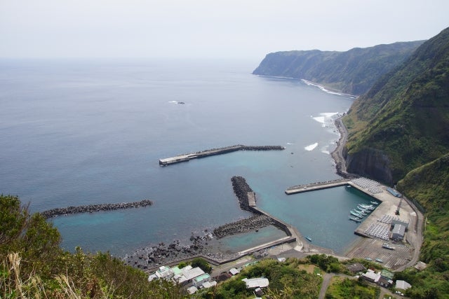 海岸沿いの港がある山間部の風景。青い海と緑の丘が広がっている。