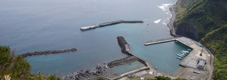 海岸沿いの港がある山間部の風景。青い海と緑の丘が広がっている。