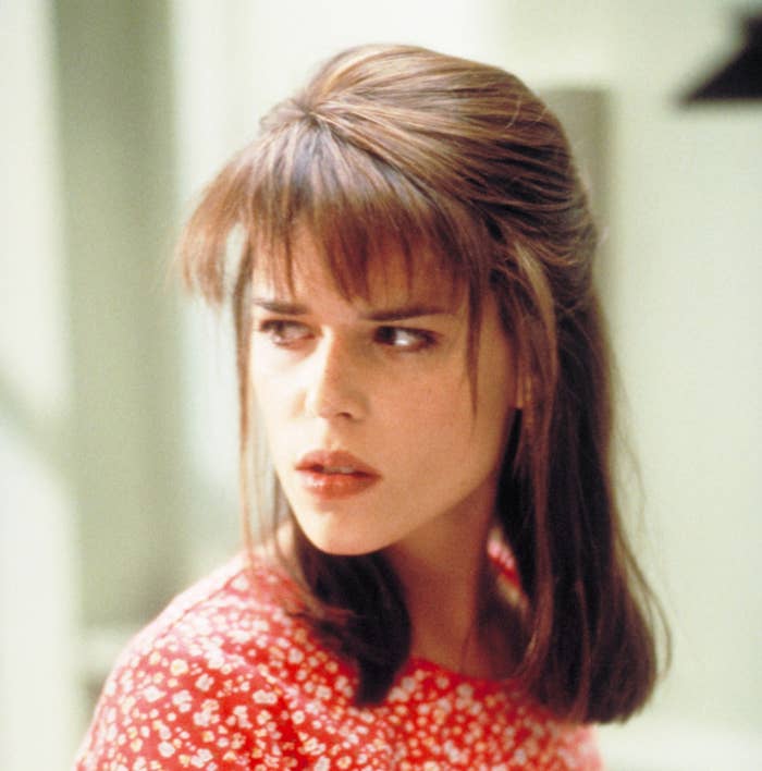 Person with medium-length hair glancing to the side, wearing a patterned top