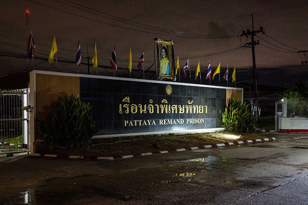Entrance of Pattaya Remand Prison astatine night, with flags and a salient motion successful Thai and English