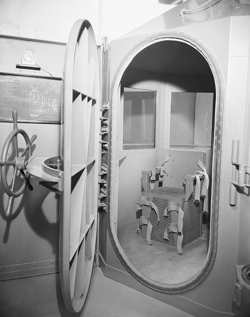 Oval-shaped metallic enclosure doorway open, revealing instrumentality wrong a vault-like room. Large instrumentality grip is connected the door