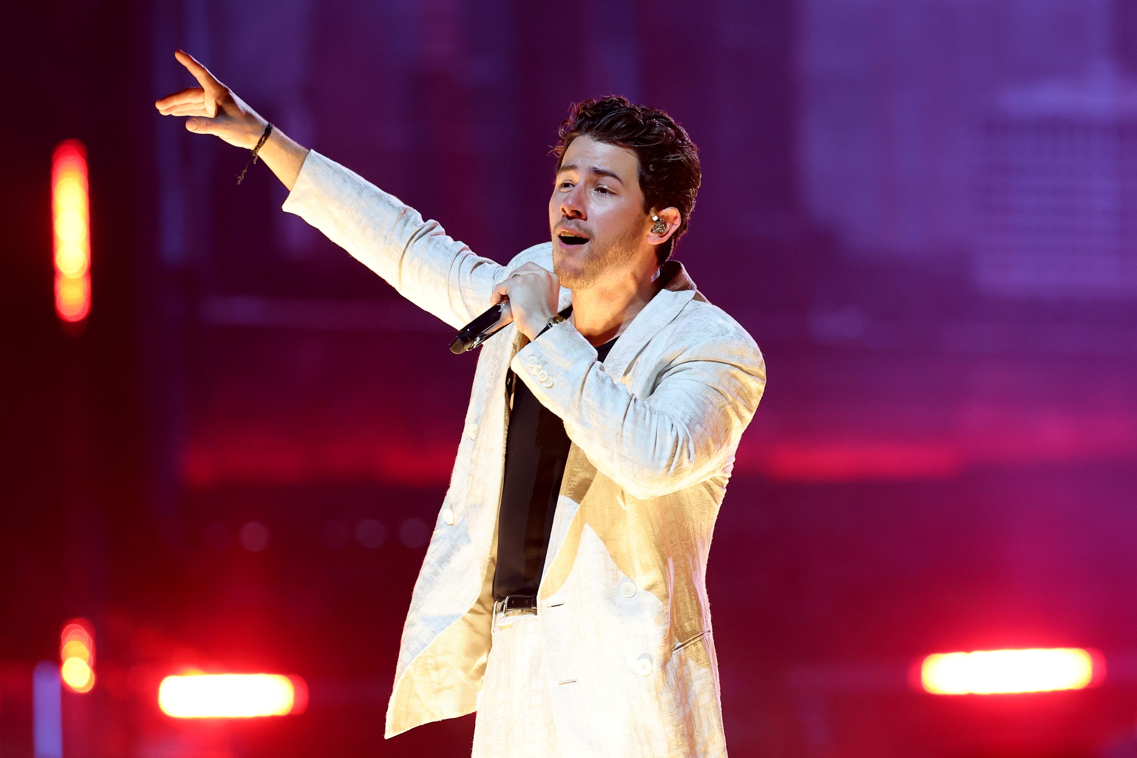 Singer performing energetically on stage, wearing a sleek suit and holding a microphone
