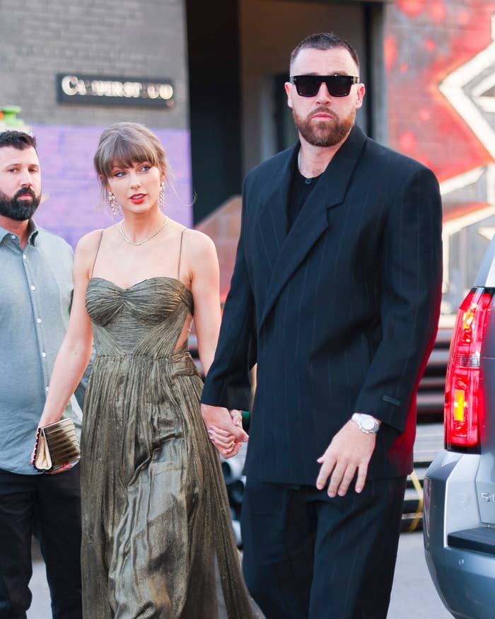 Two radical   walking unneurotic  astatine  an event. One wears a flowing gown, the different   a tailored suit. They look  assured  and are holding hands