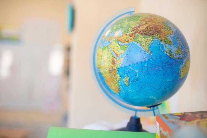 A globe on a stand, showing parts of Europe, Asia, and Africa, with a blurred classroom background