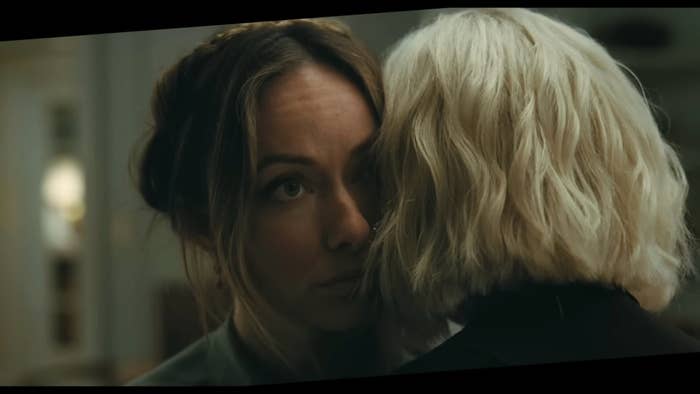Two women successful  an intimate, adjacent  clasp  indoors; 1  has brownish  hair, the different   has blonde hair