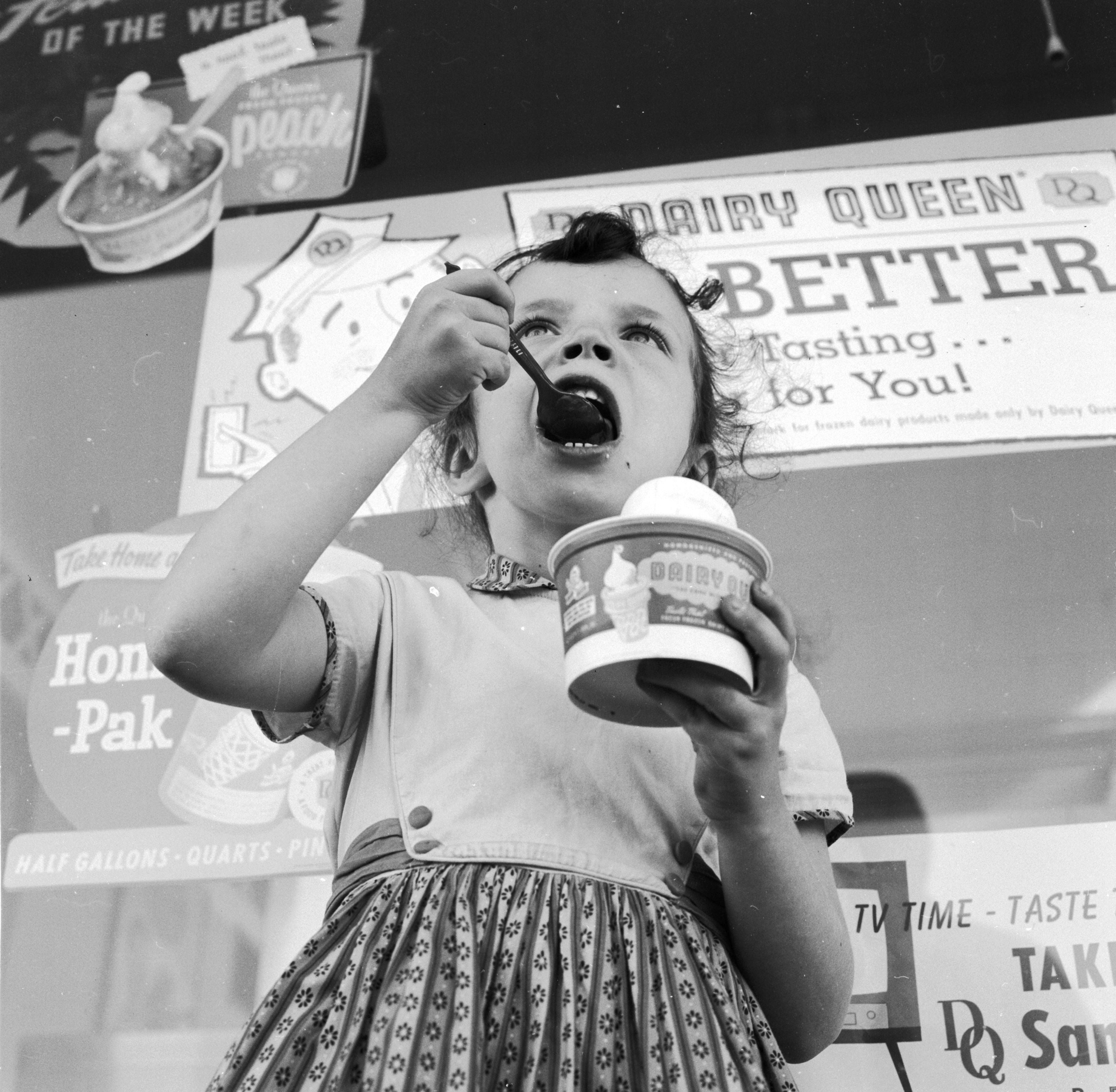 A vintage Dairy Queen with a kid eating a cupful of crystal pick outdoors