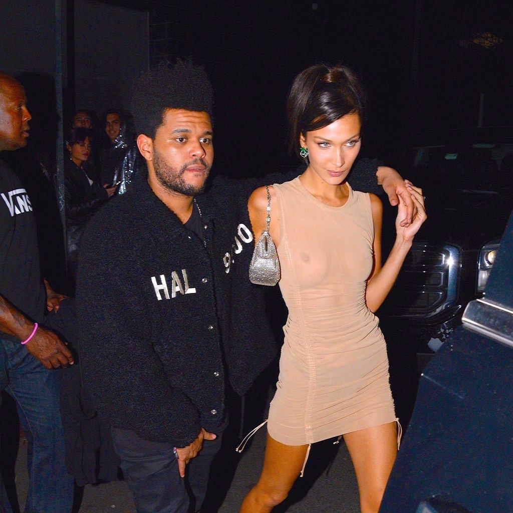 A mates is walking together; 1 is successful a textured jacket, the different successful a form-fitting sleeveless dress, with an limb astir their shoulder