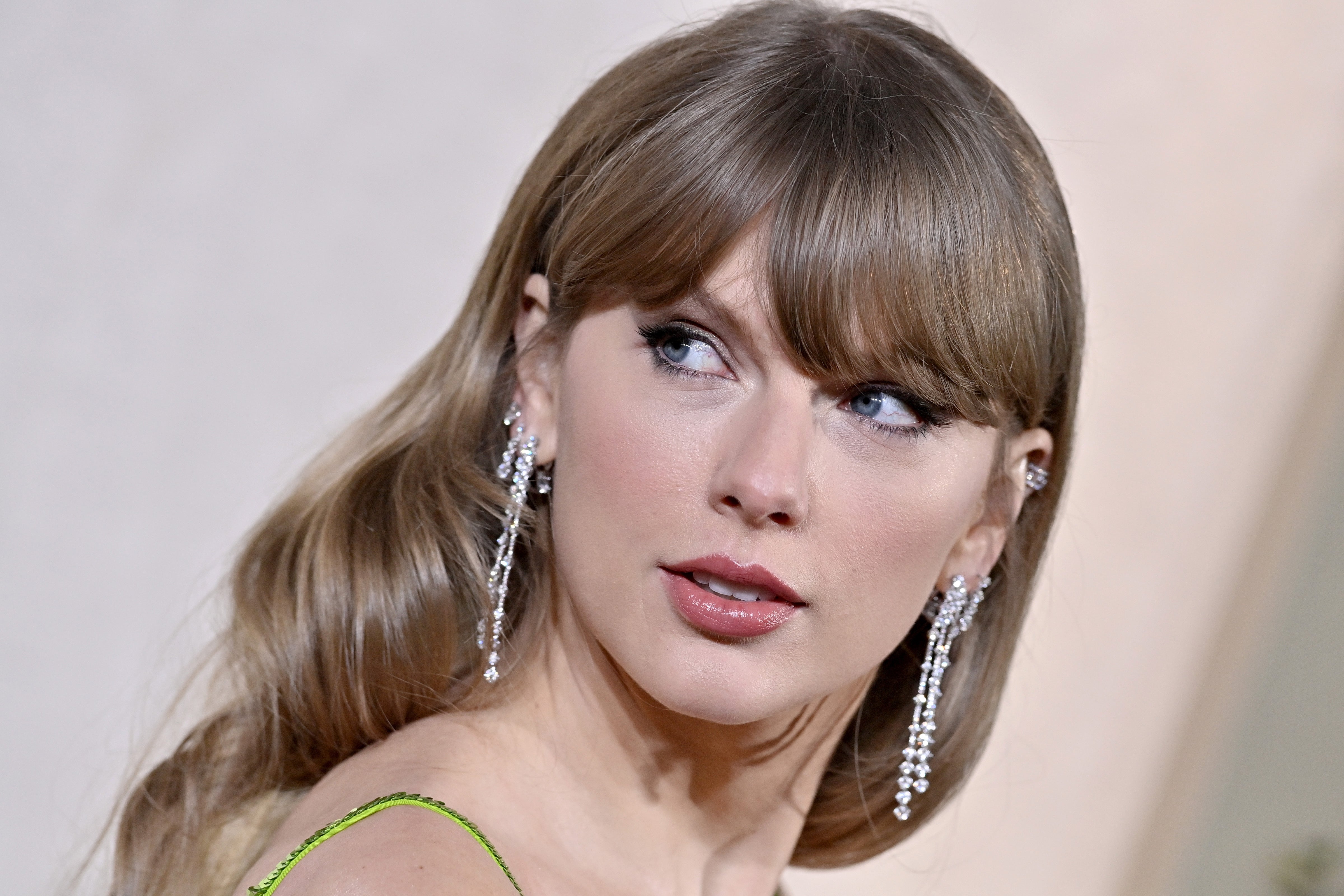 Taylor Swift connected a reddish carpet wearing elegant, sparkling earrings and wavy hairsbreadth looks to the side