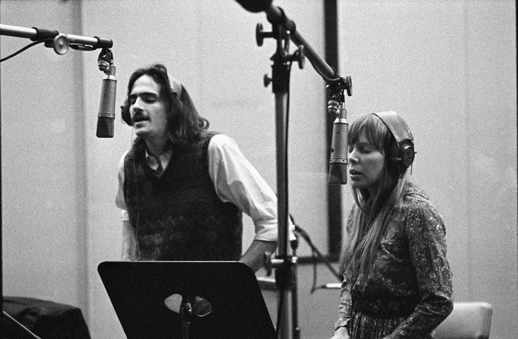 Two radical are singing into microphones successful a signaling studio, wearing headphones