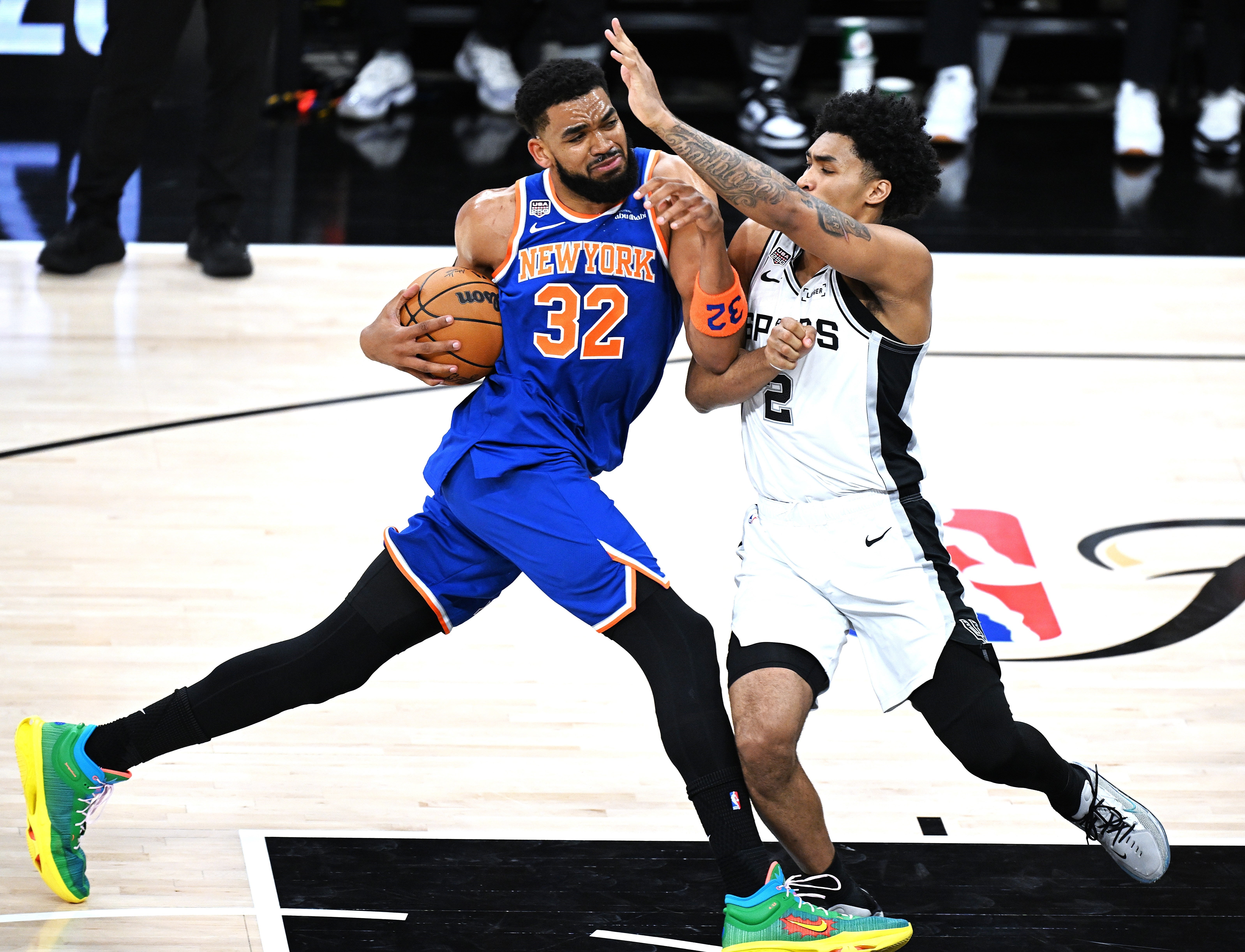 Basketball players successful enactment during a game, 1 successful bluish jersey driving to the handbasket portion the different defends successful a achromatic jersey