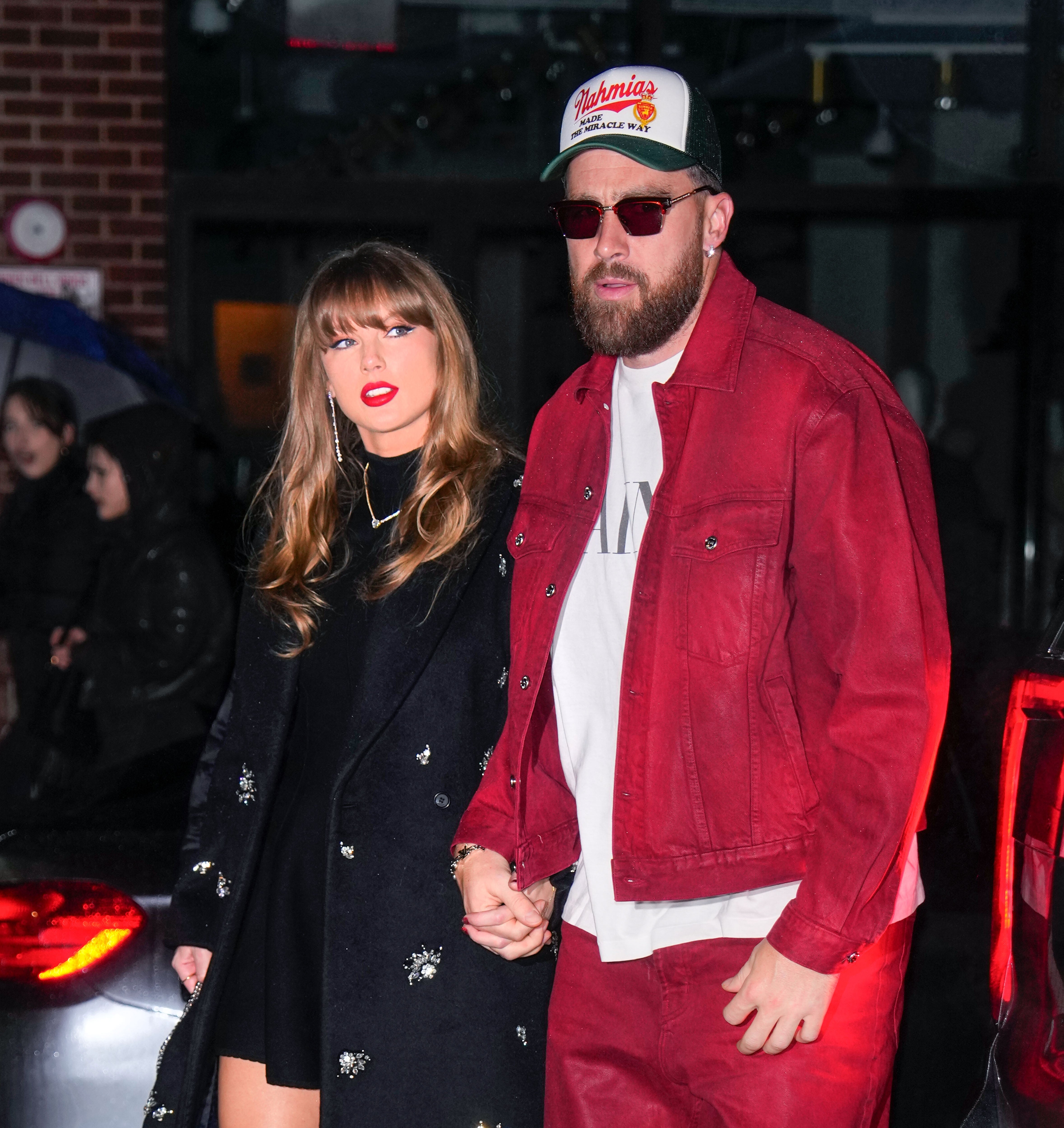 Taylor Swift successful an embellished overgarment and Travis Kelce successful a casual overgarment and headdress walking and holding hands