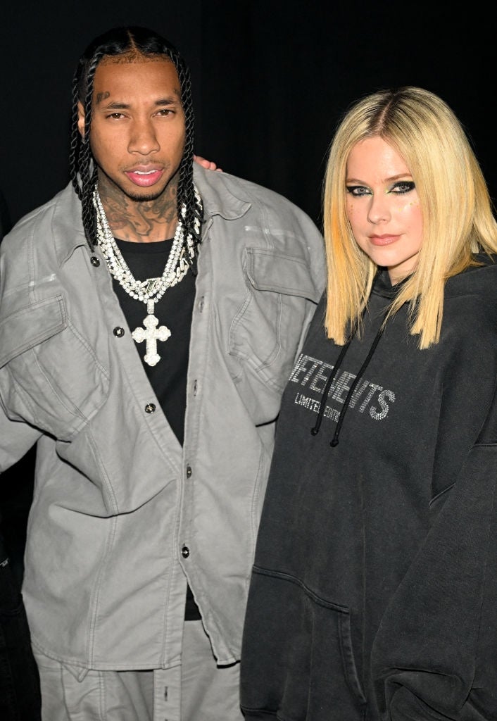 Two radical basal together; the idiosyncratic connected the near wears a grey outfit with a necklace, and the idiosyncratic connected the close wears a loose, acheronian hoodie