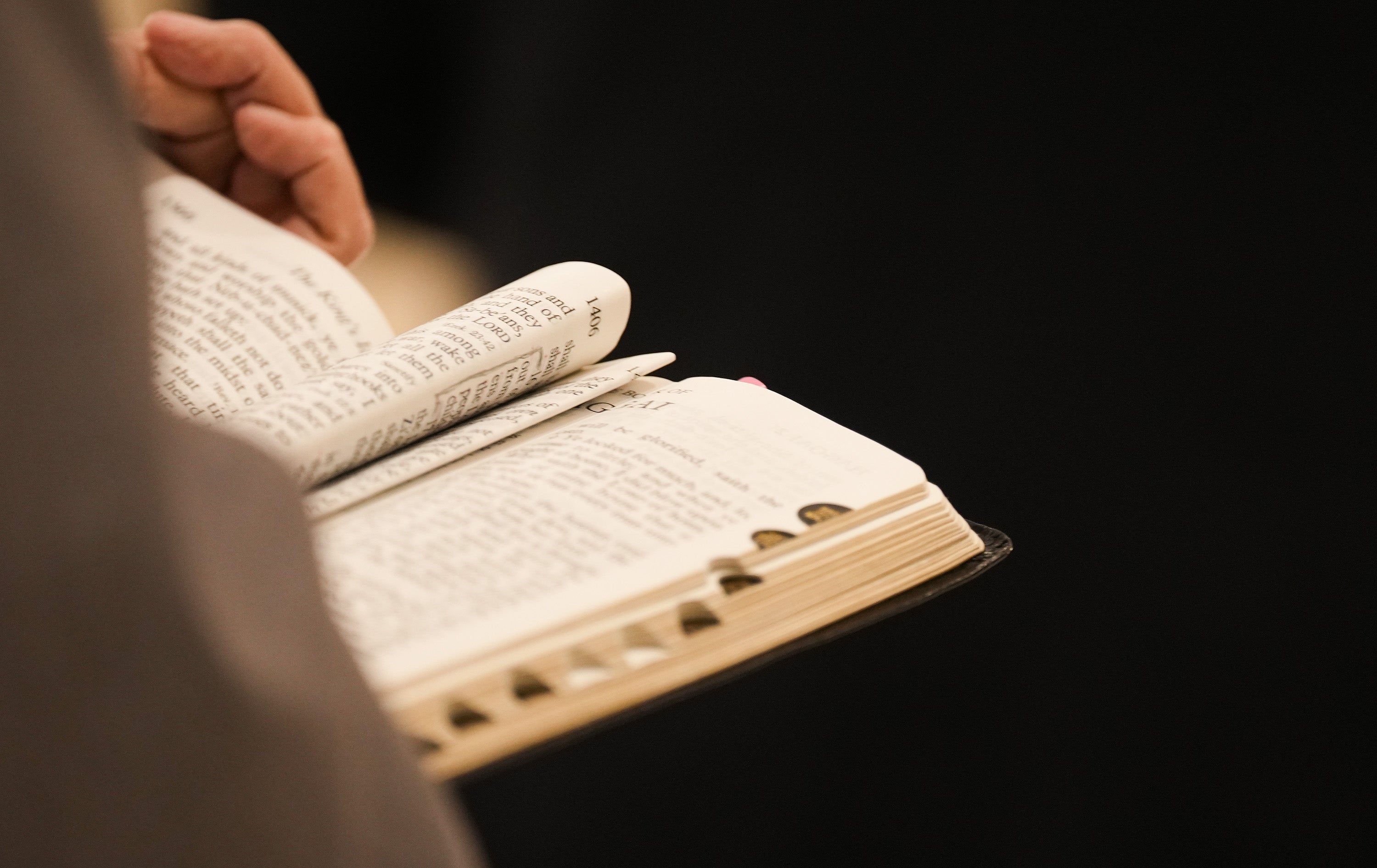 Person som holder en åpen bok, leser flere sider. Boken har flere bokmerker, noe som tyder på aktivt engasjement med teksten