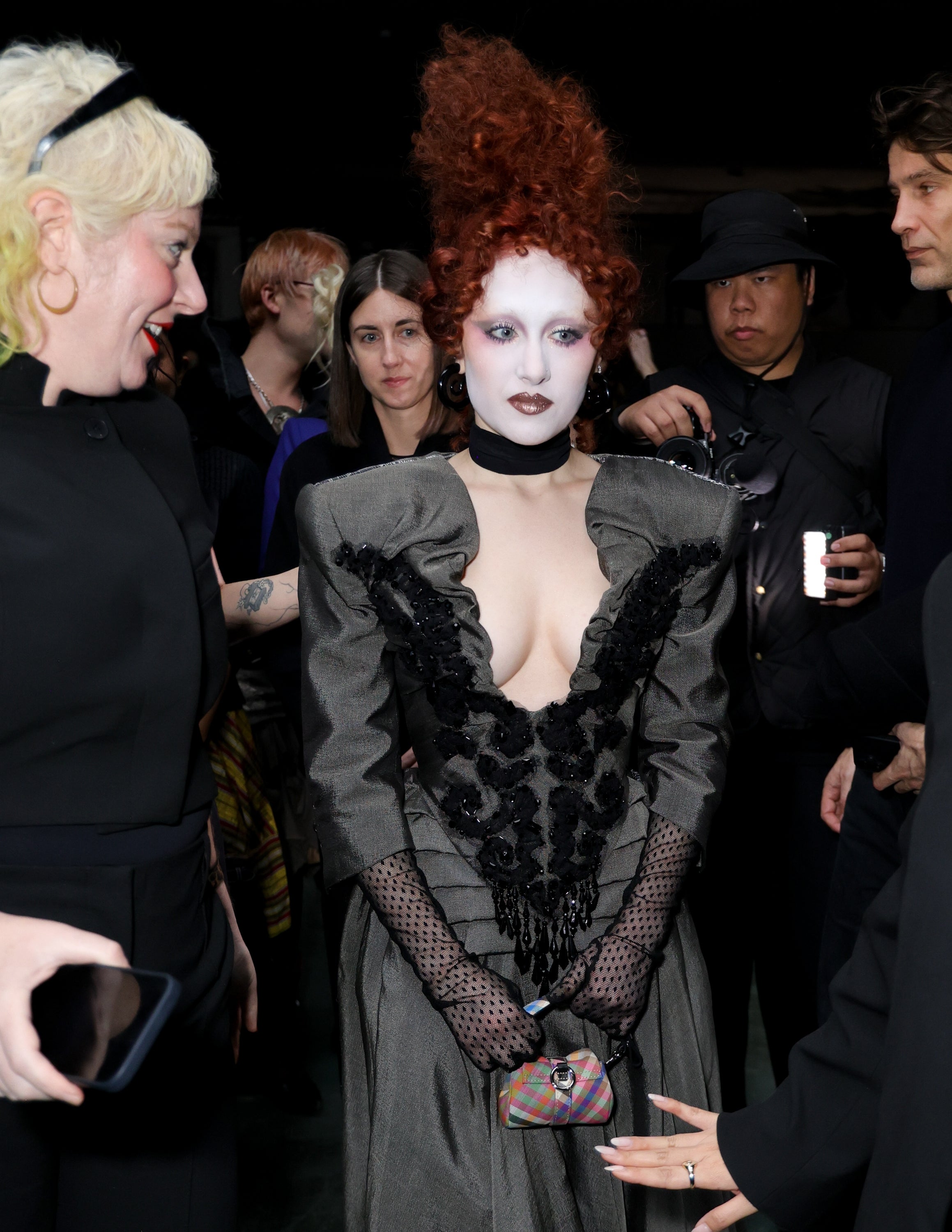 Person wearing a dramatic, Victorian-inspired gown with black lace details and puffed sleeves, surrounded by people at an event