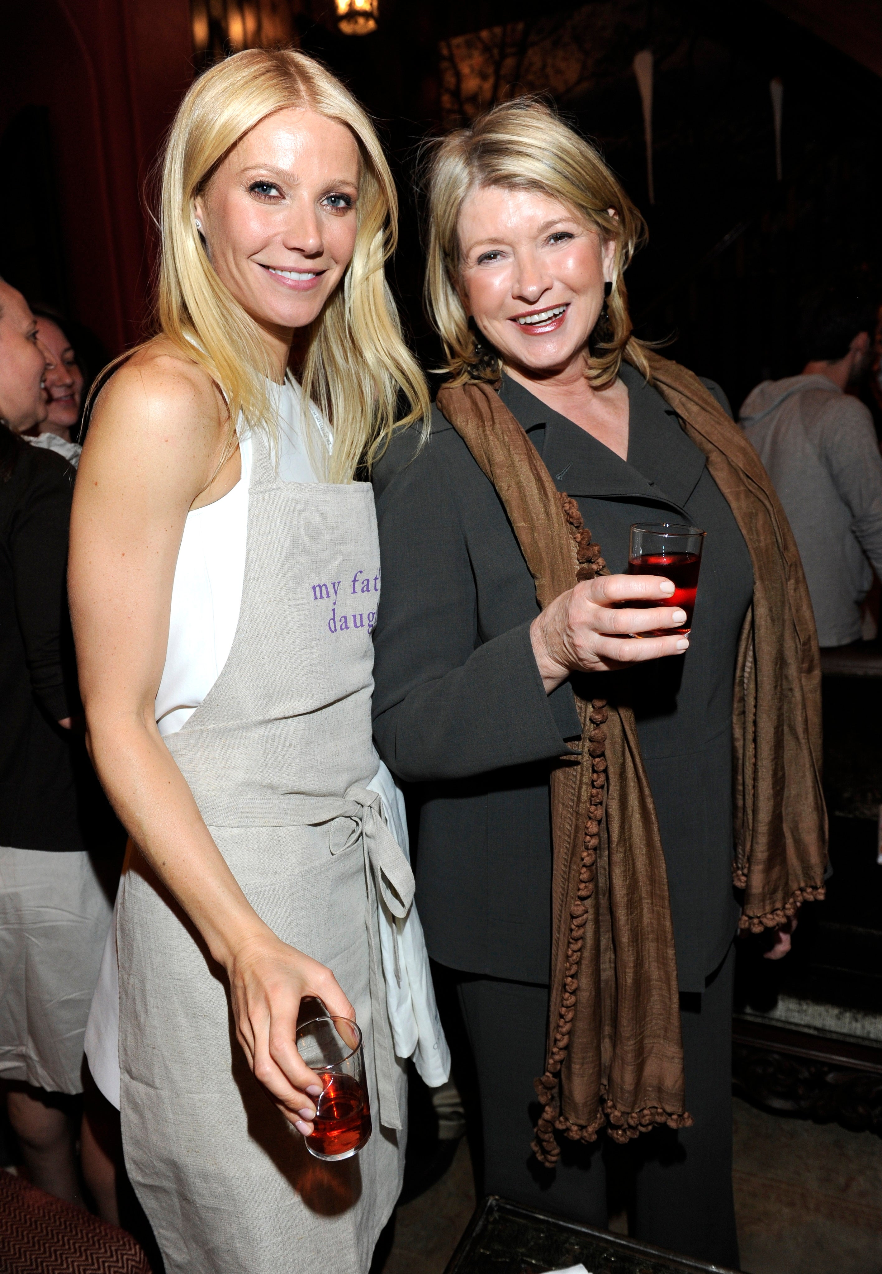 Gwyneth Paltrow and Martha Stewart smile while holding drinks at an event