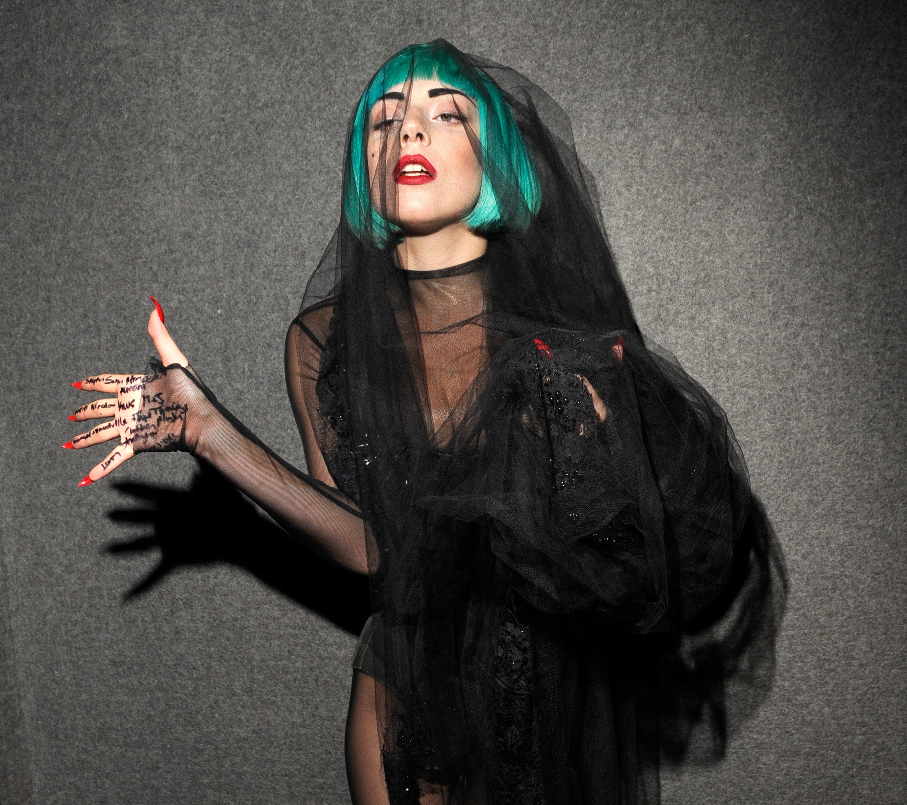 Lady Gaga wears a bright turquoise bob and a black veil with red acrylic nails