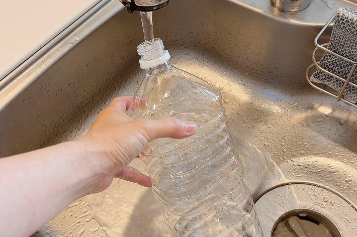 蛇口からペットボトルに水を注いでいる様子。シンクで作業中。