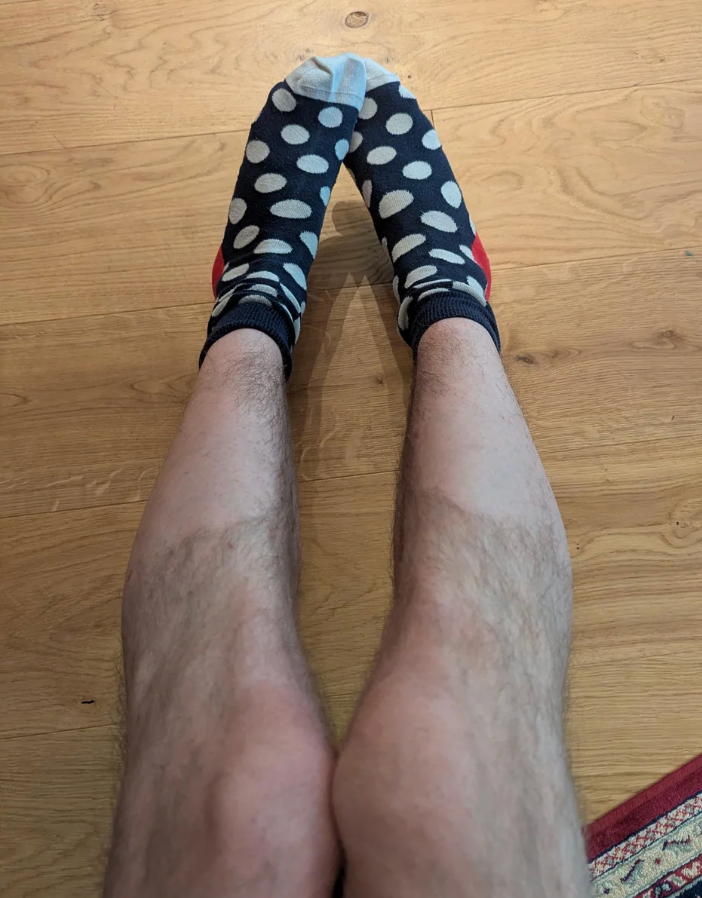 Person's legs connected a woody floor, wearing mismatched polka dot socks