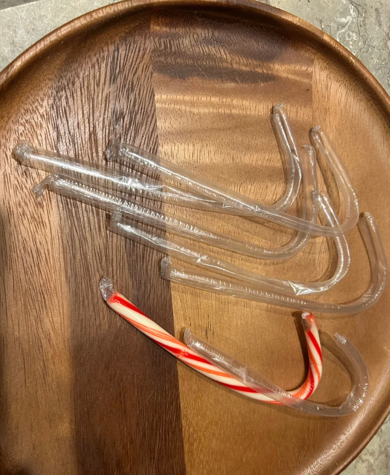 Clear and 1 striped candy cane wrapper connected a woody plate