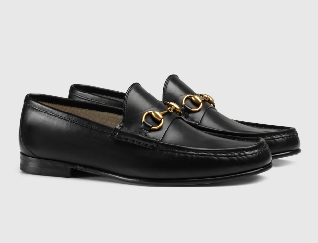 Black leather loafers with gold horsebit detailing on the front