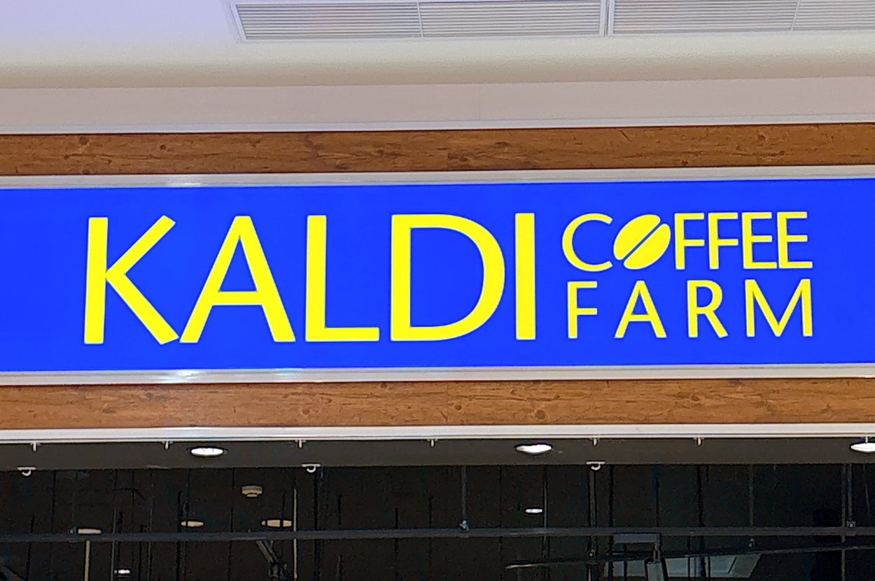 カフェ「カルディコーヒーファーム」の店頭看板。店内には商品が並んでいる。