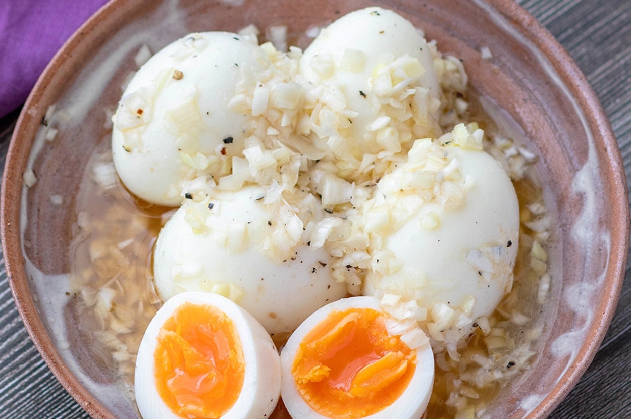 器に盛られた半熟卵の上に玉ねぎが載せられた料理。