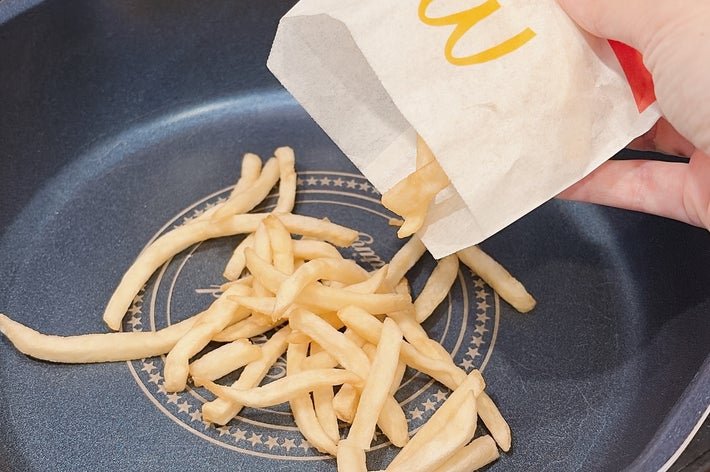 フライパンにフライドポテトを袋から出している様子。