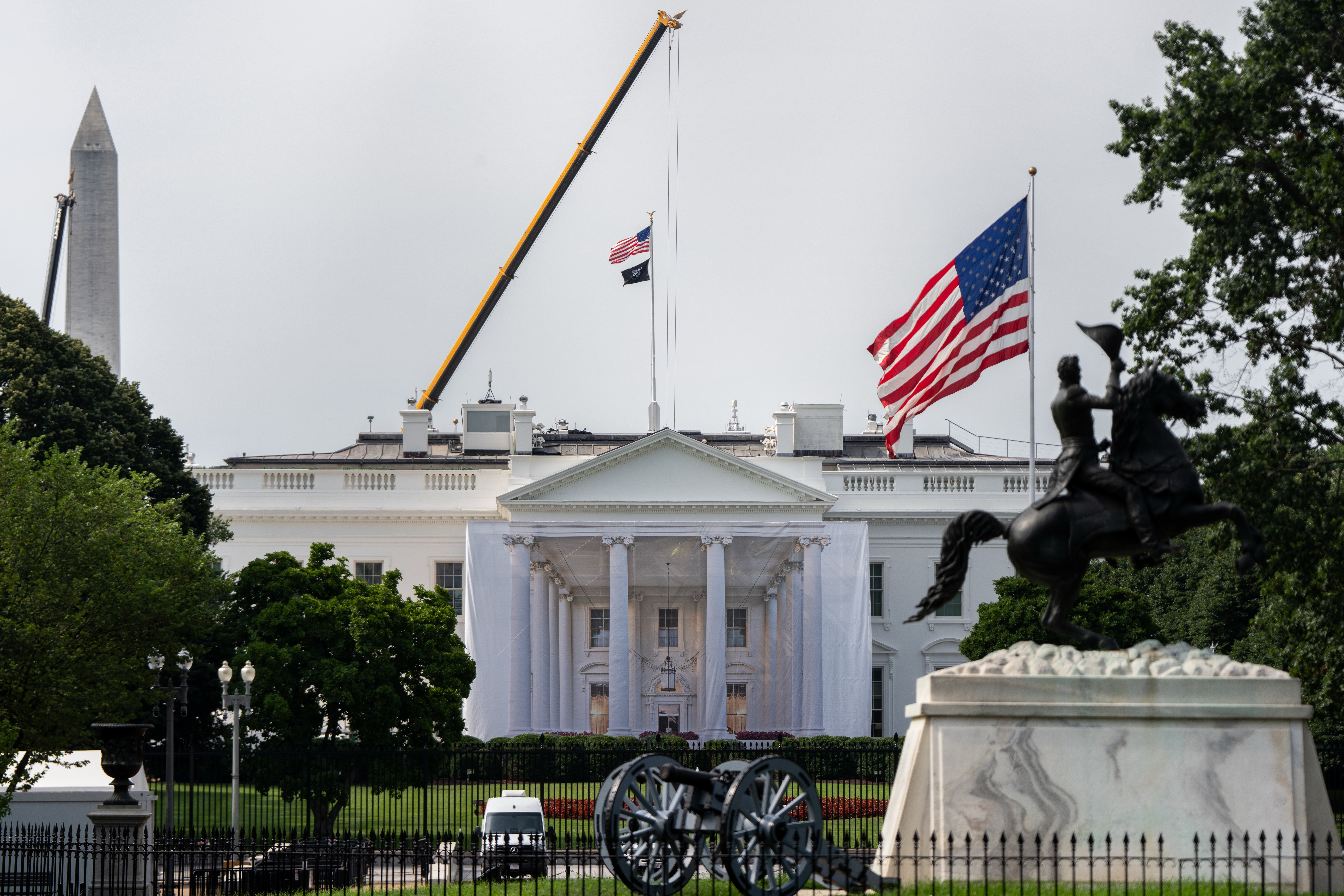 Det hvite hus med kraner, flagg fra USA og Washington DC og en rytterstatue i forgrunnen