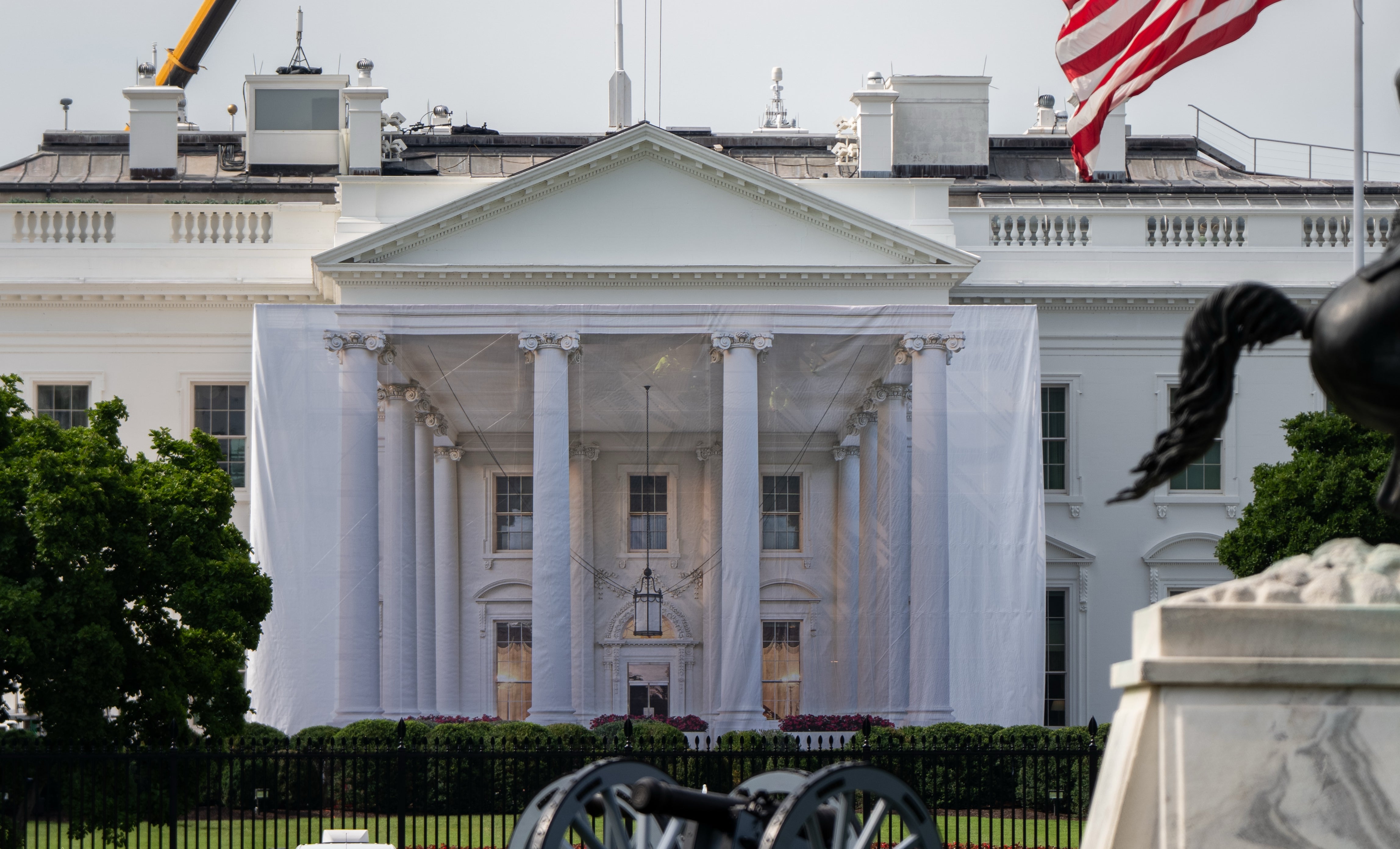Det hvite hus med kraner, flagg fra USA og Washington DC og en rytterstatue i forgrunnen