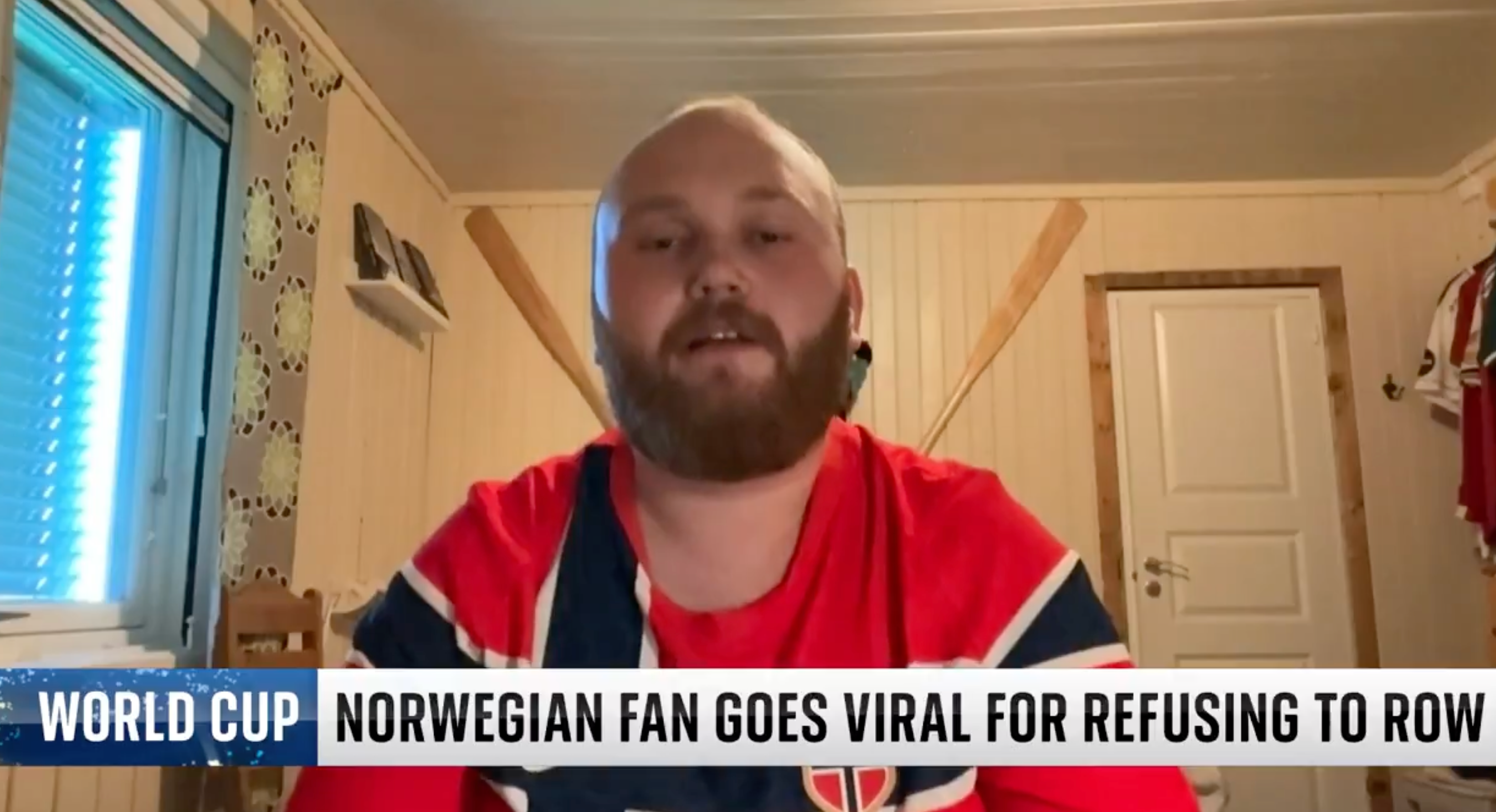 En person i et rom har på seg en skjorte med et flagglignende design, med en overleggstekst som leser,