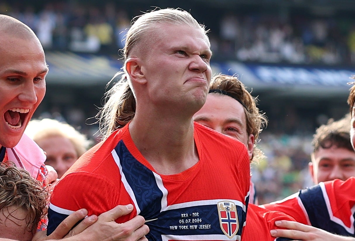 En gruppe fotballspillere i festlig omfavnelse under en kamp, alle i stripete og solide trøyer, og uttrykker spenning og triumf på banen