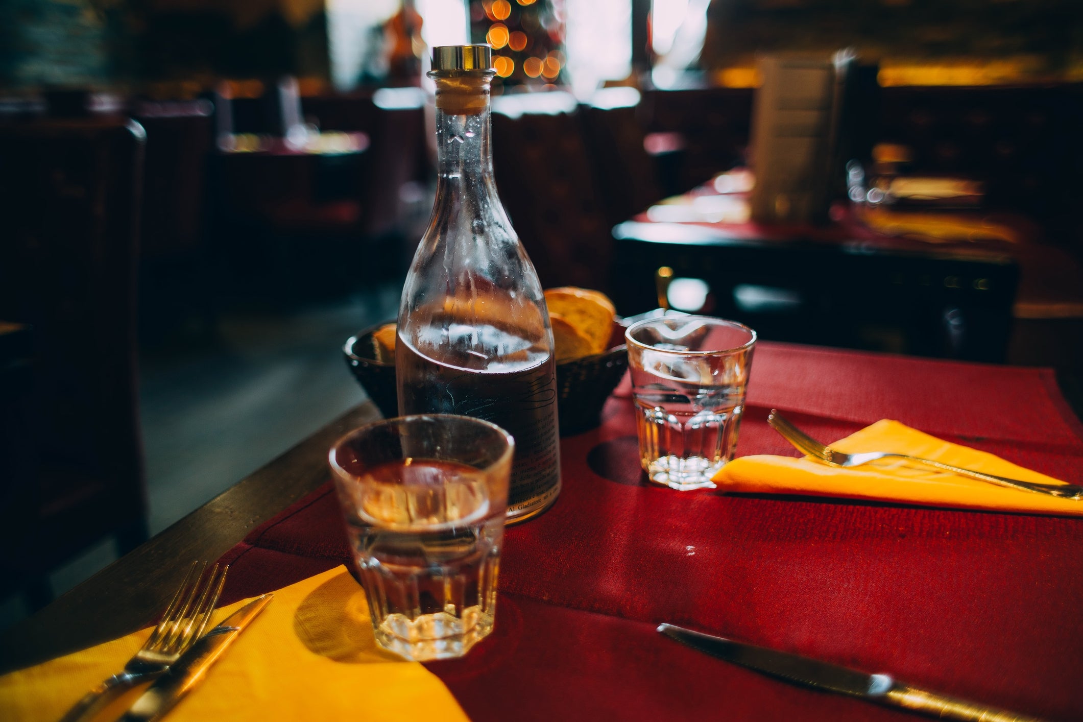 Table set with glasses, a bottle of water, and bread in a cozy restaurant setting. Suitable for dining