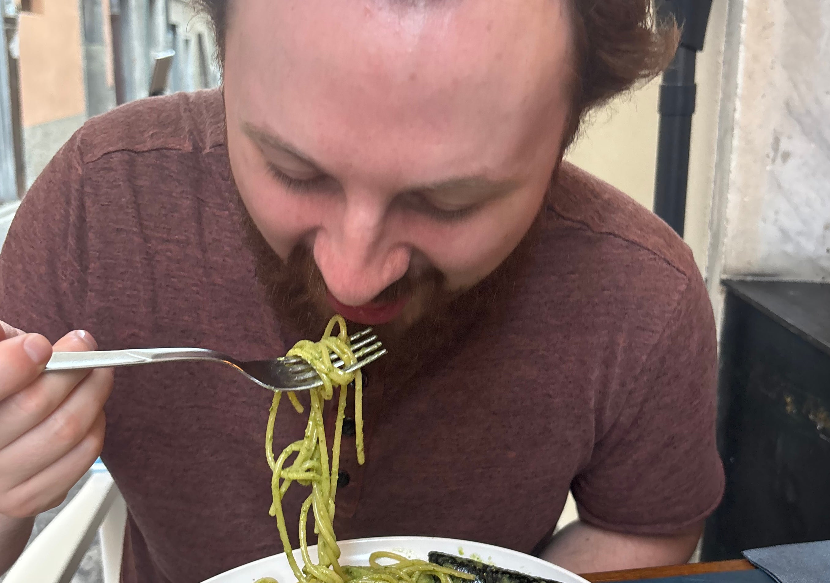 Person enjoying a seafood pasta dish at an outdoor restaurant, capturing a travel dining experience