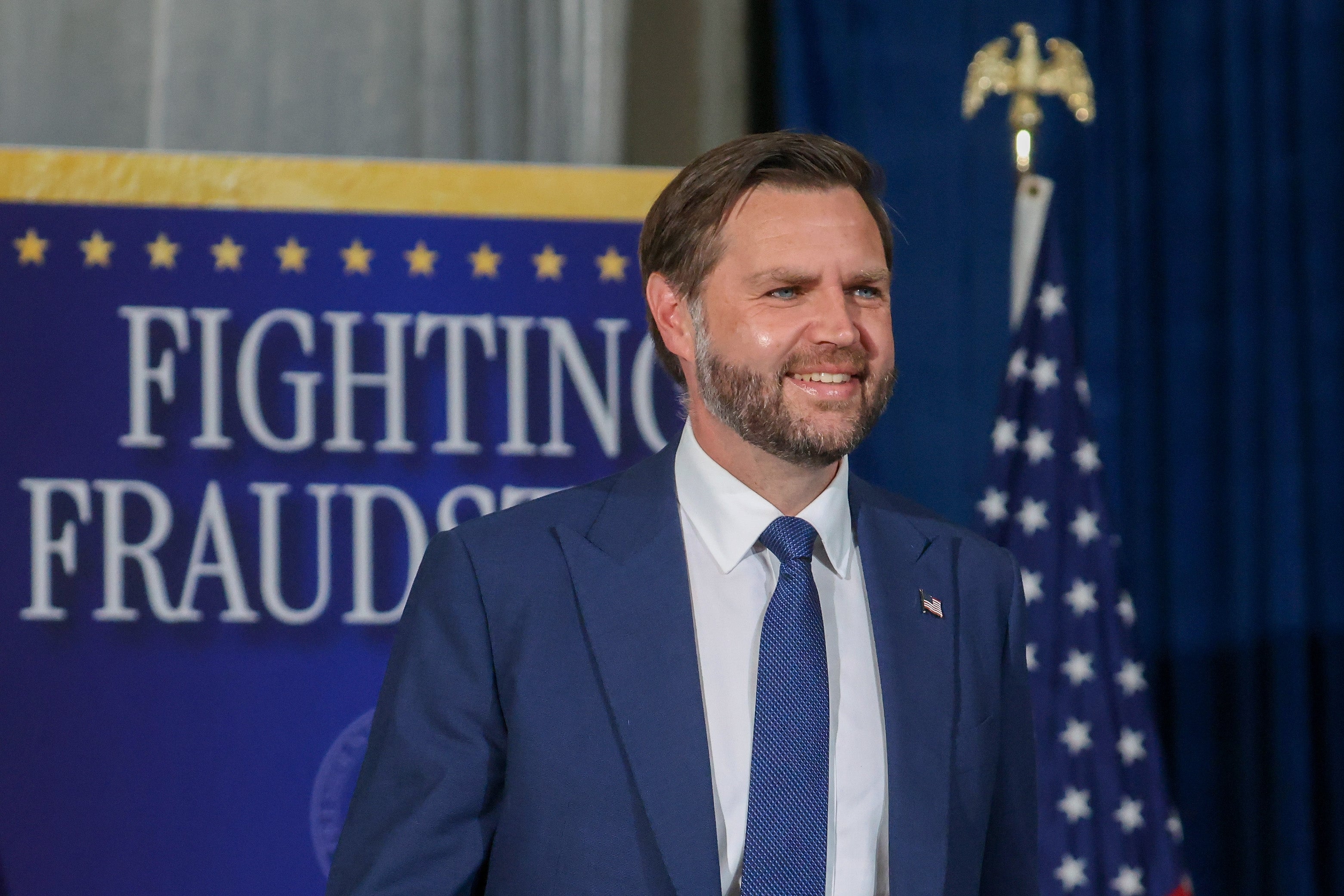 Person successful a suit lasting successful beforehand of a "Fighting Fraud" banner, with the US emblem disposable successful the background