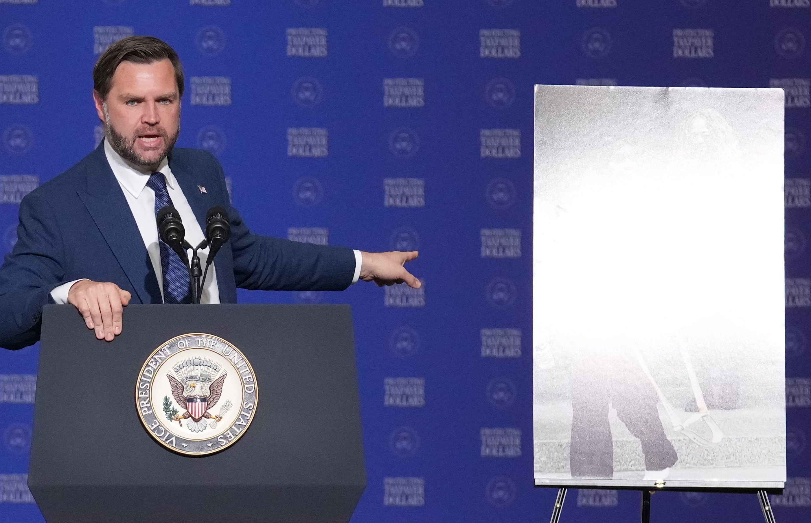 Man successful a suit speaking down a podium with graphs displayed, nether the banner "Protecting Taxpayer Dollars," successful Milwaukee, Wisconsin