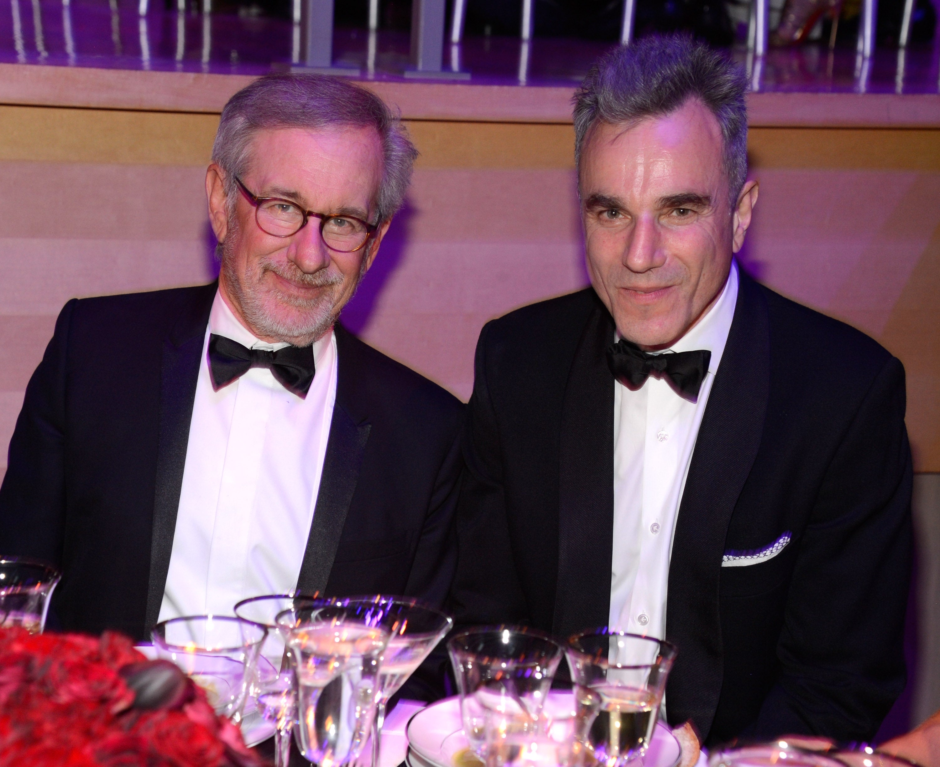 Steven Spielberg and Daniel Day-Lewis wear suits and sit together while surrounded by drinks