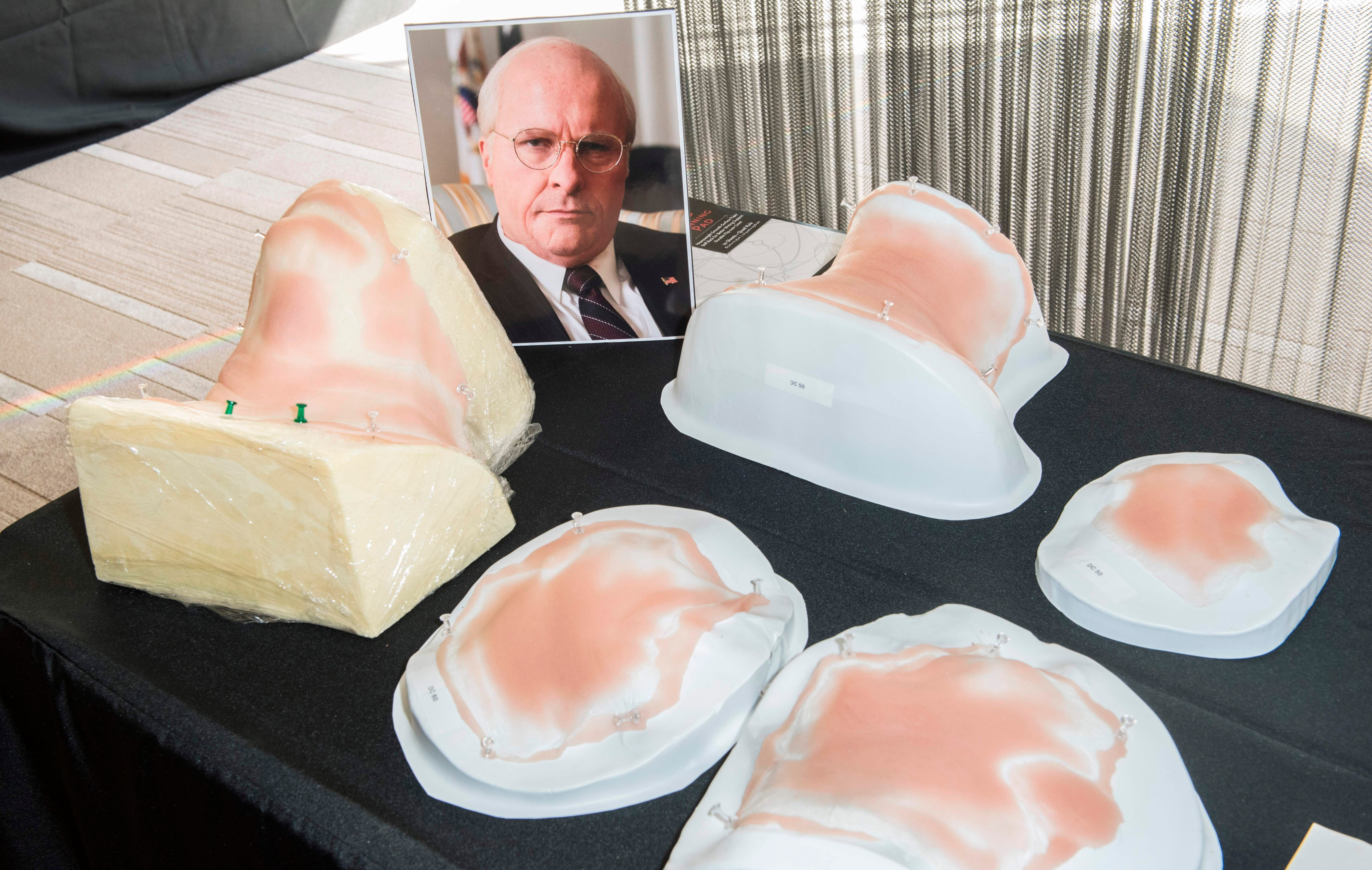 Display of prosthetic jowls on a table with a photo of Christian Bale portraying the character of Dick Cheney in Vice