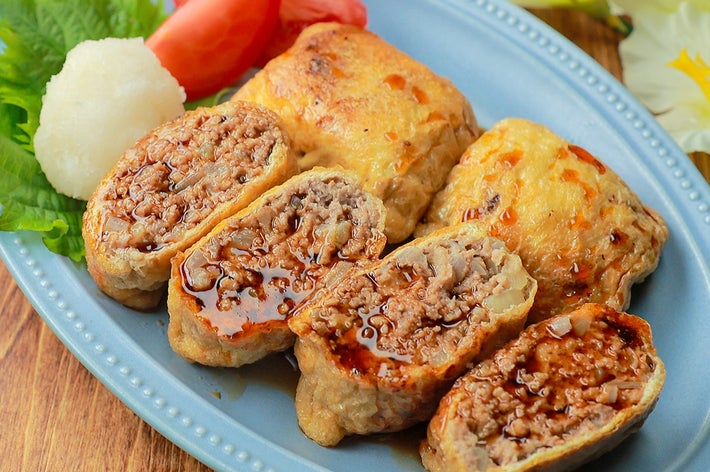 お皿に盛られたハンバーグの詰め物料理。横にトマトと大根おろしが添えられている。